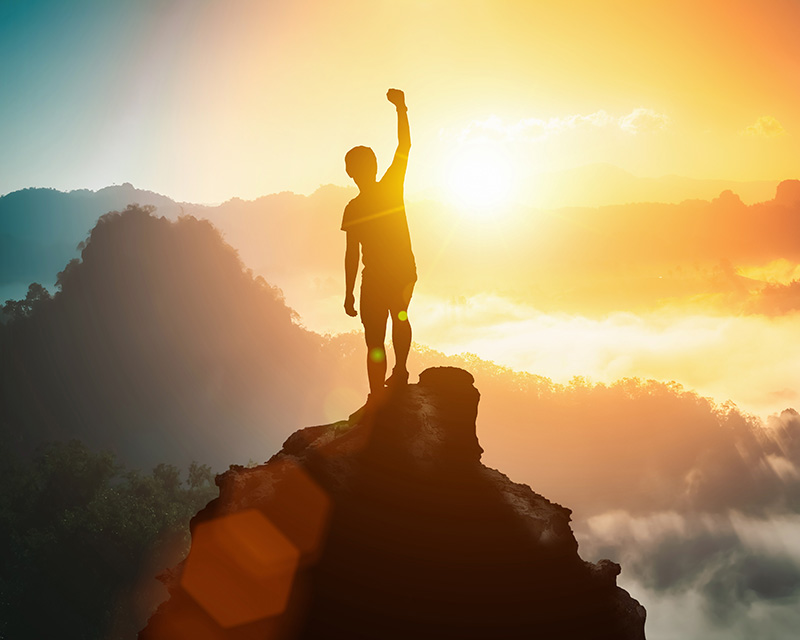 Man standing on top of a mountain in the sunlight